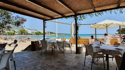 Tables sous l'auvent de La Terraza del Náutico, au bord de la plage de Las Fuentes en été